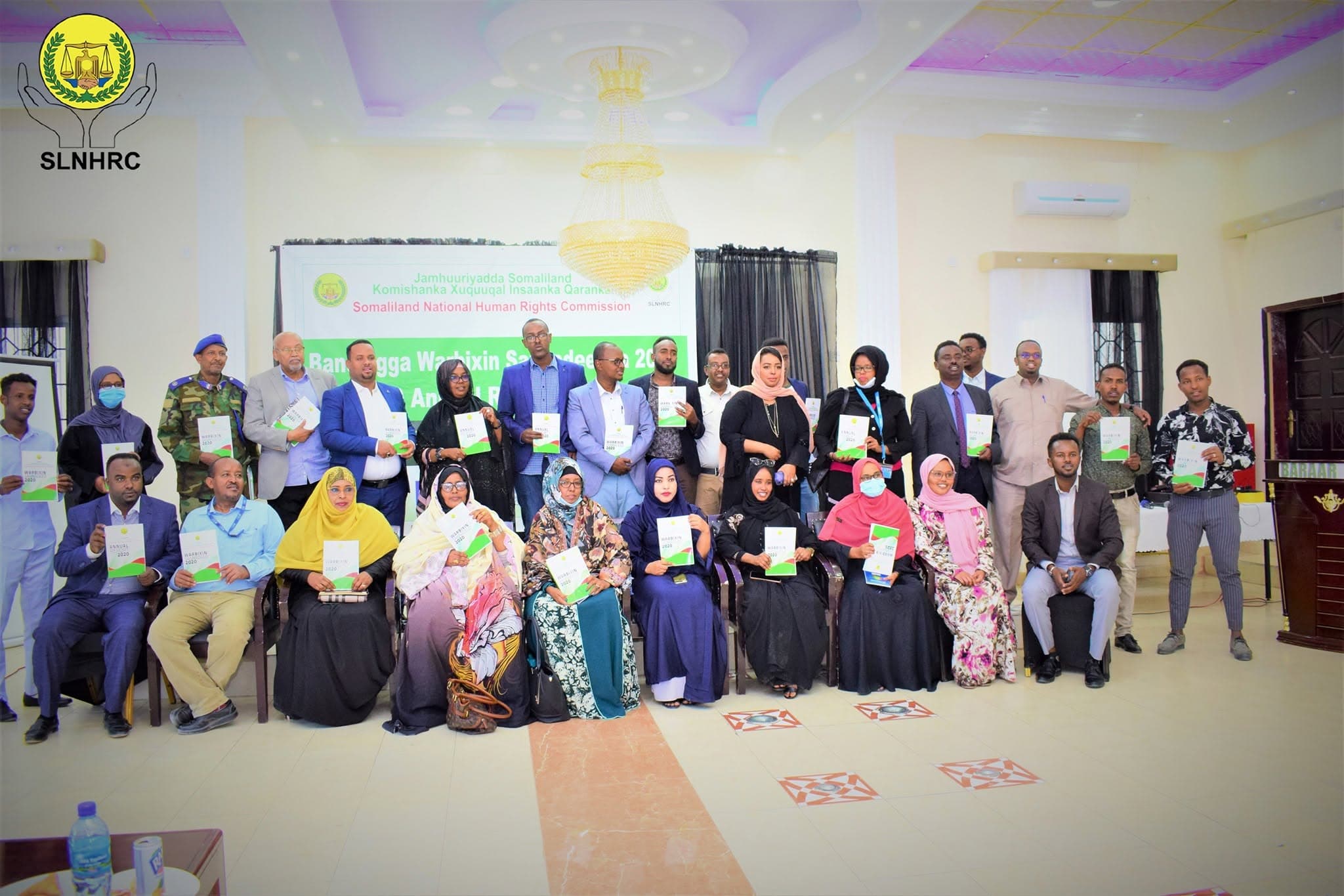Participants hold copies of the Commission's 2020 Annual Report during a group photograph.
